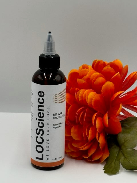 A bottle of LOC LOVE Daily Hair Oil with an orange flower in the background. Natural Hair Growth Products